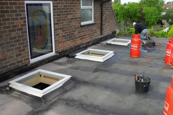 Balmoral Flat Roofing operatives laying and heat-sealing felt on a flat roof extension