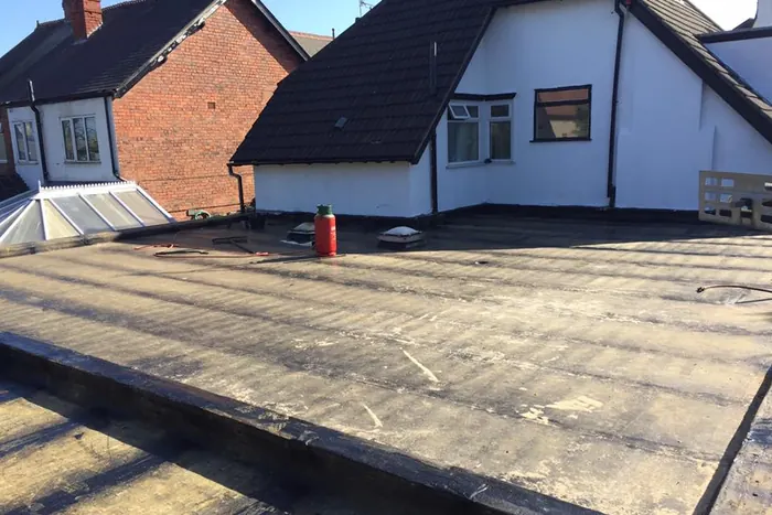 Worn flat roof covering before replacement, showing ponding and surface failure