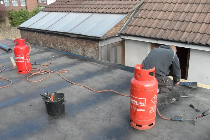 Liquid waterproofing coating being applied across a large flat roof with a roller