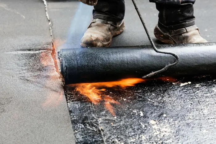 Operative heat-sealing a torch-on felt lap on a flat roof